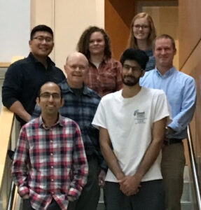 seven Carter lab standing in flannel shirts and comfortable clothes standing on a stairway with Dr. Charlie Carter