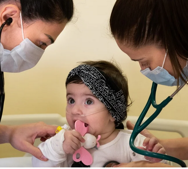two doctors leaning over a baby with stethoscopes