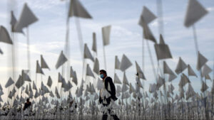 A person walks through a field of white flags.