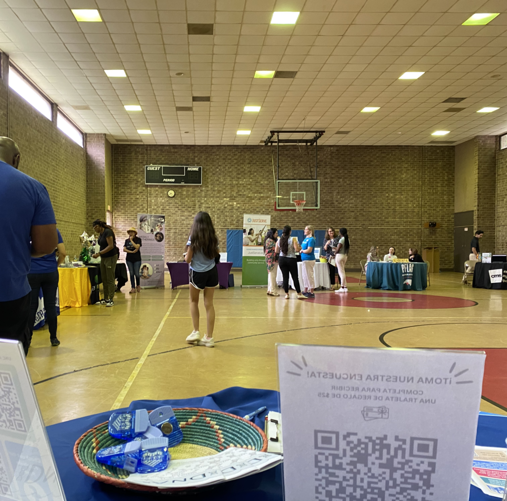 a view of the community resource fair with sifferent colorful tables and attendess walking and talking to the community representatives there. 