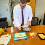 Gray Gereau, PhD cuts his cake at his PhD party.